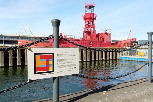 Photograph showing the installed sign with an AR marker designed by the Silent Voice for his poem titled Beneath the Waves