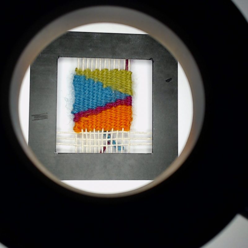 a woven marker within a black square frame seen through a ring light